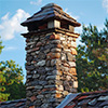 The stone chimney on the roof of a residential home.